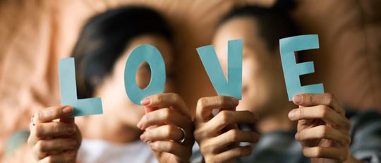 Female LGBTQ couple holding up the letters of 