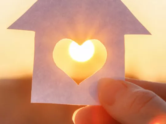 paper cut-out of house with the sun behind it