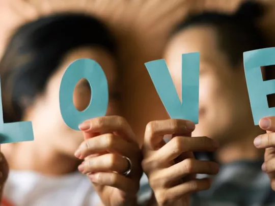 Female LGBTQ couple holding up the letters of